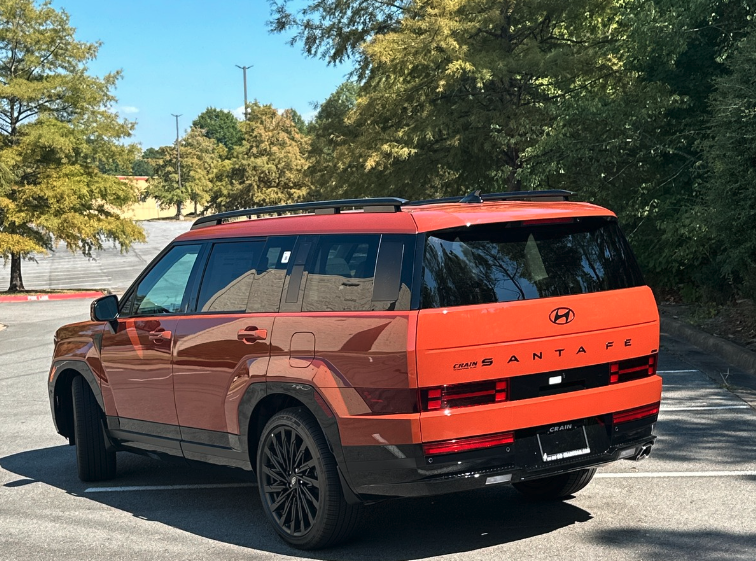 Rear view of a red 2025 Hyundai Santa Fe parked near fall foliage in Fayetteville, Arkansas.